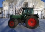 Używany ciagnik rolniczy Fendt 310 na tle zabudowań gospodrstwa widom na lewy bok pojazdu 