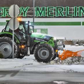 Zielony traktor Deutz-Fahr wraz z pomarańczowym pługiem do śniegu PSV 301 odśnieża parking Leroy Merlin www.korbanek.pl