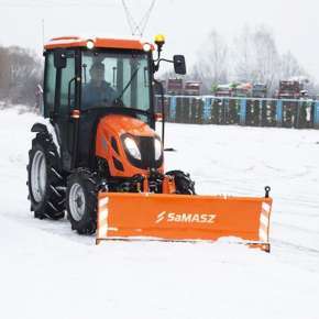 Pomarańczowy mały traktor komunalny z pomarańczowym pługiem do śniegu SMART 180 odśnieża plac www.korbanek.pl