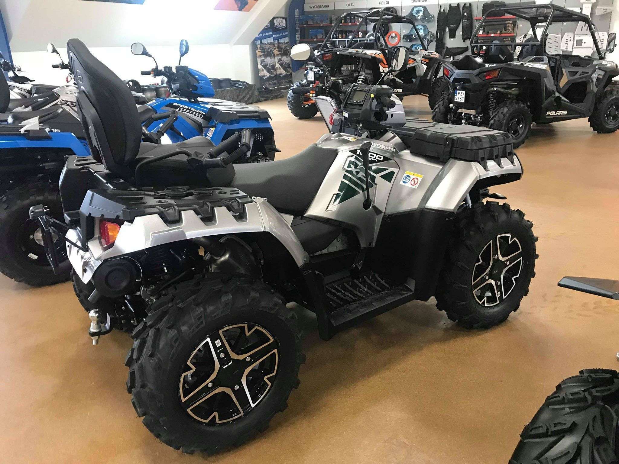 Srebrny metalik Quad Polaris Sportsman 1000 Touring na tle innych modeli pojazdów Polaris