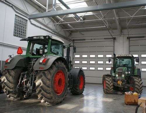 Dwa traktory Fendt w dużej hali warsztatowej