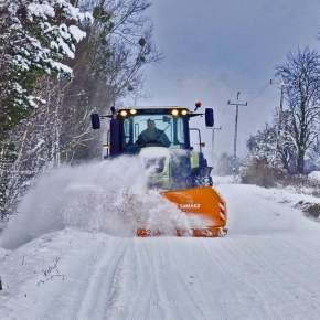 Widok od przodu pług odśnieży Samasz typ Alps 301 z zielonym traktorem rolniczym odśnieża polną drogę www.korbanek.pl
