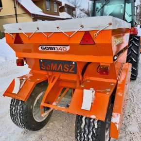 Widok z tyłu pomarańczowej piaskarki zaczepianej do traktora GOBI 140 firmy Samasz z plandeką www.korbanek.pl
