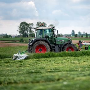 Zielone kosiarki dyskowe firmy TALEX podczas koszenia łąki z ciągnikiem rolniczym FENDT