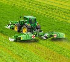 Kosiarki dyskowe GigaCUT firmy Samasz wraz z zielonym ciągnikiem rolniczym koszą trawę na łące