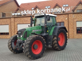 Ciągnik Fendt 818 Vario TMS na tle magazynu części Korbanek widok z lewej strony