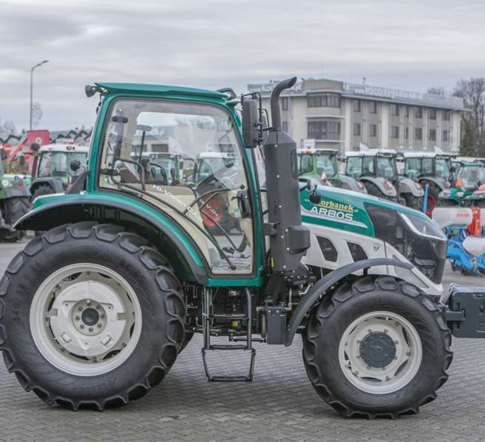 Ciągnik Arbos 5115 Advanced widok z boku Bok ciągnika arbos 5115 advanced w tle biurowiec korbanek.pl