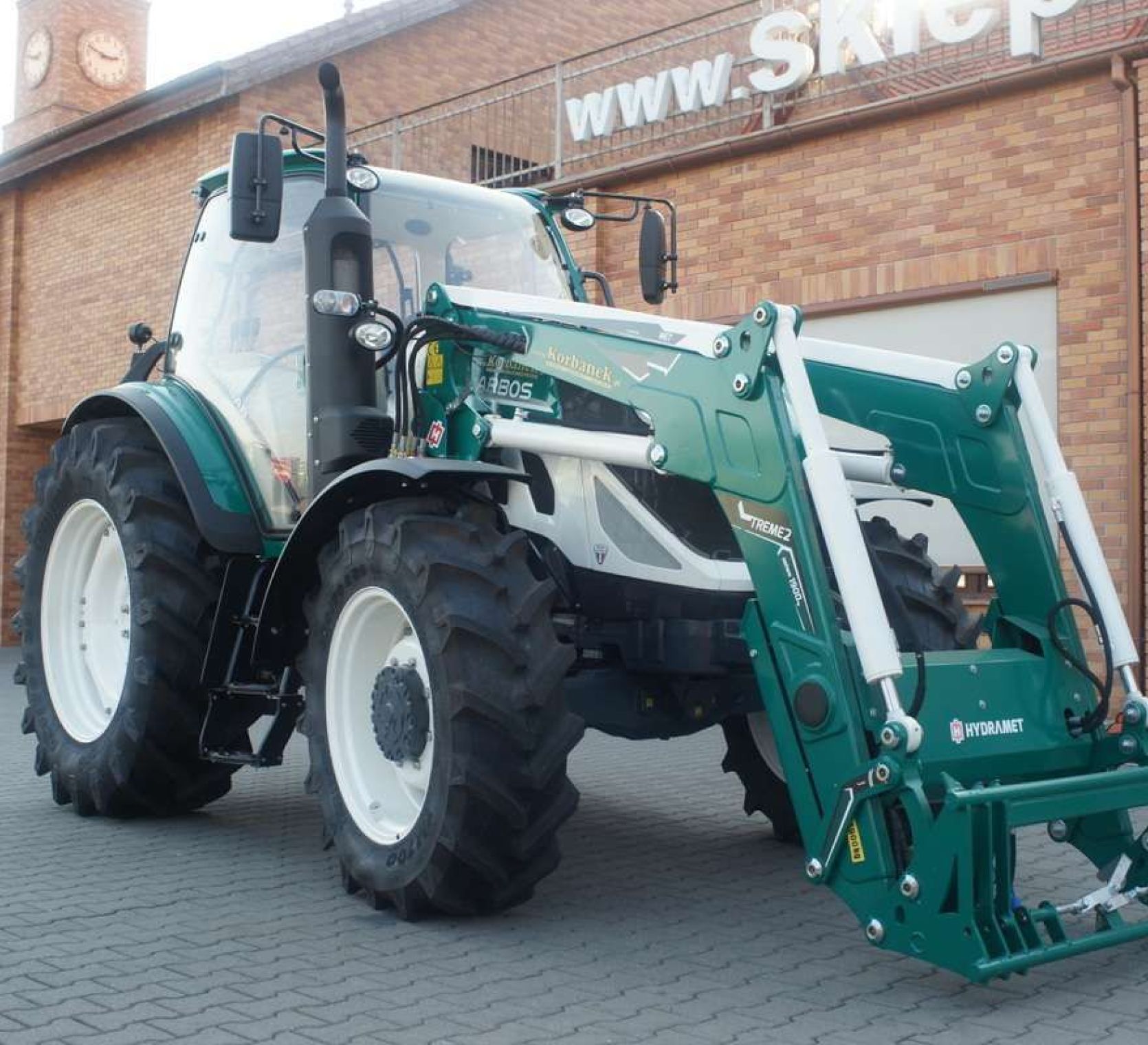ciagnik arbos 5130 z ladowaczem hydramet xtreme 2 ciagnik arbos 5130 na tle magazynu czesci korbanek zamontowany ladowacz hydramet w kolorze traktora