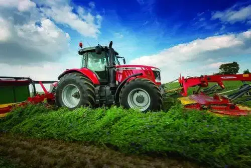 Ciągnik Massey Ferguson na polu w trakcie pracy z kosiarką Fella